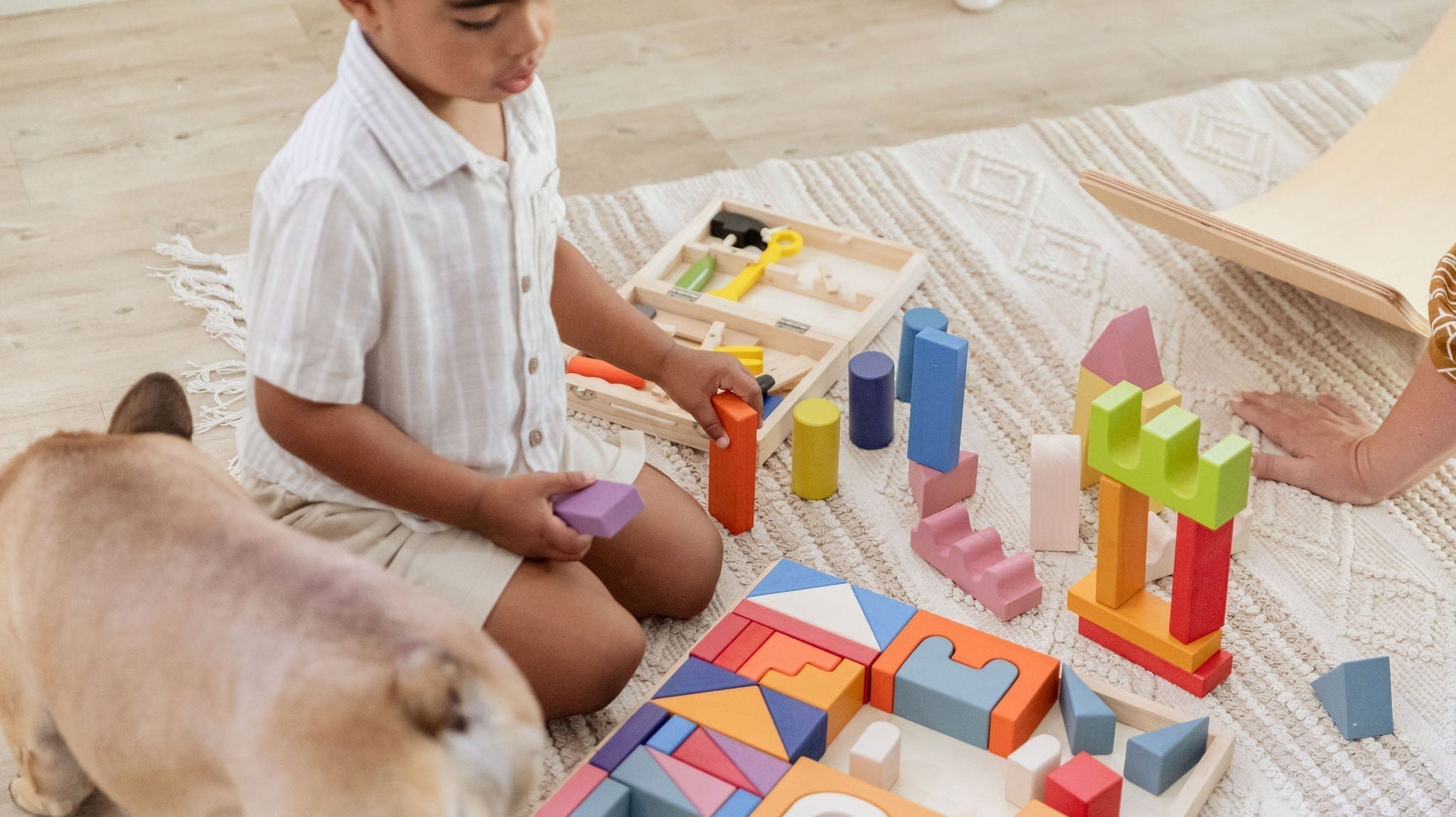 Child playing with wooden open-ended toys on a wooden floor - Tiny Tree Toys South Africa