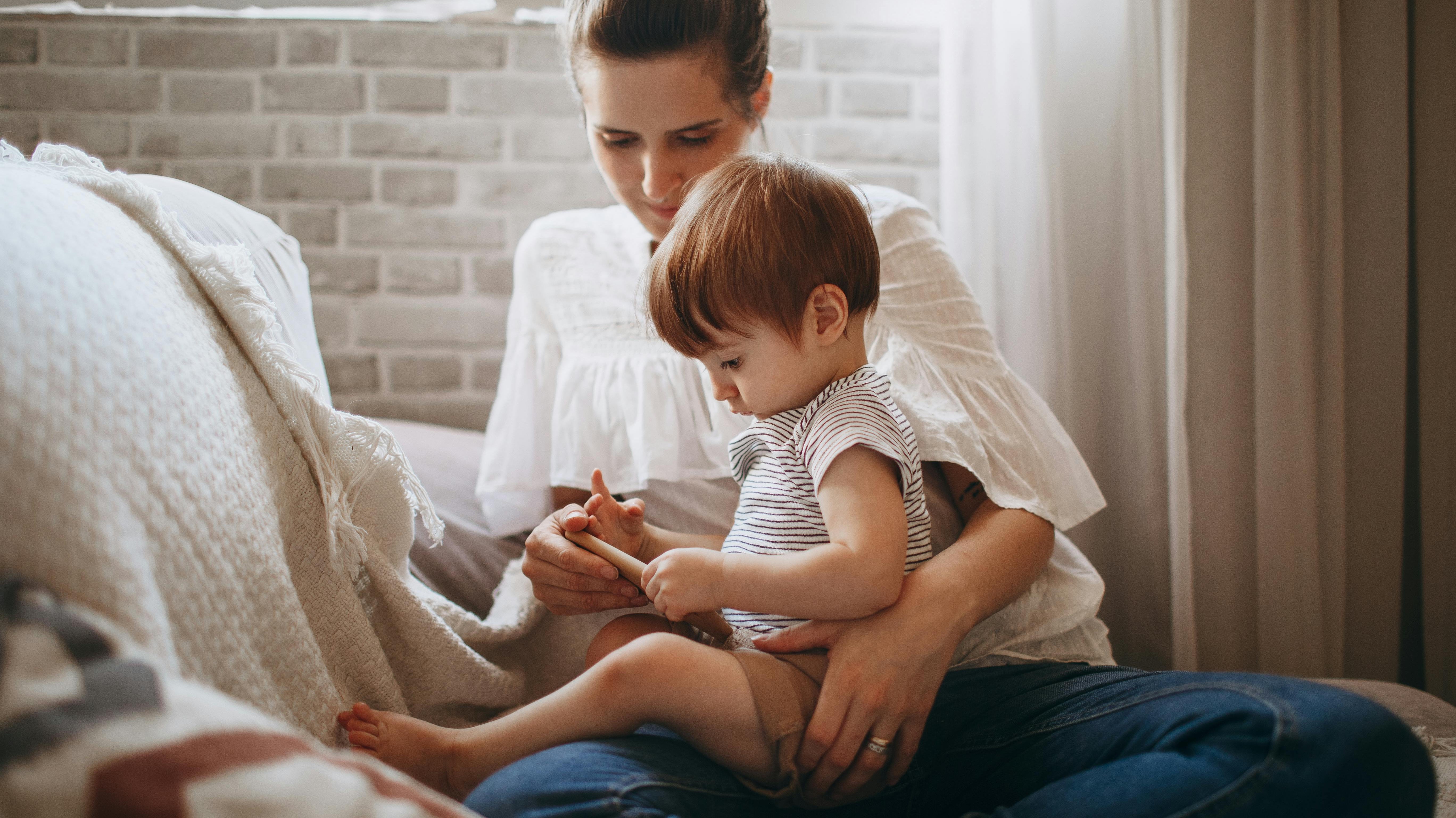 Parent calmly comforting distressed toddler on lap.