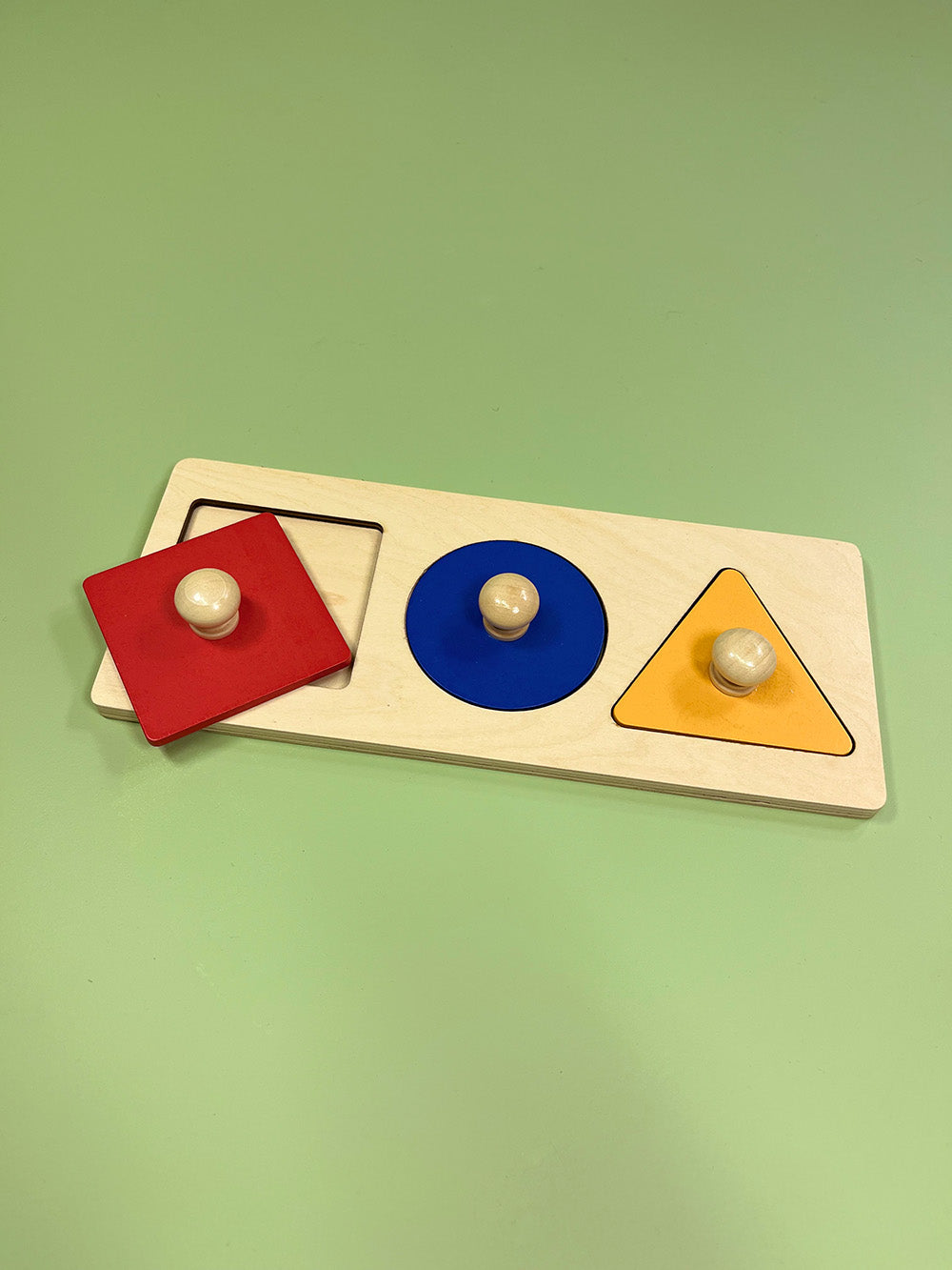Colorful wooden shape sorting toy on a green background