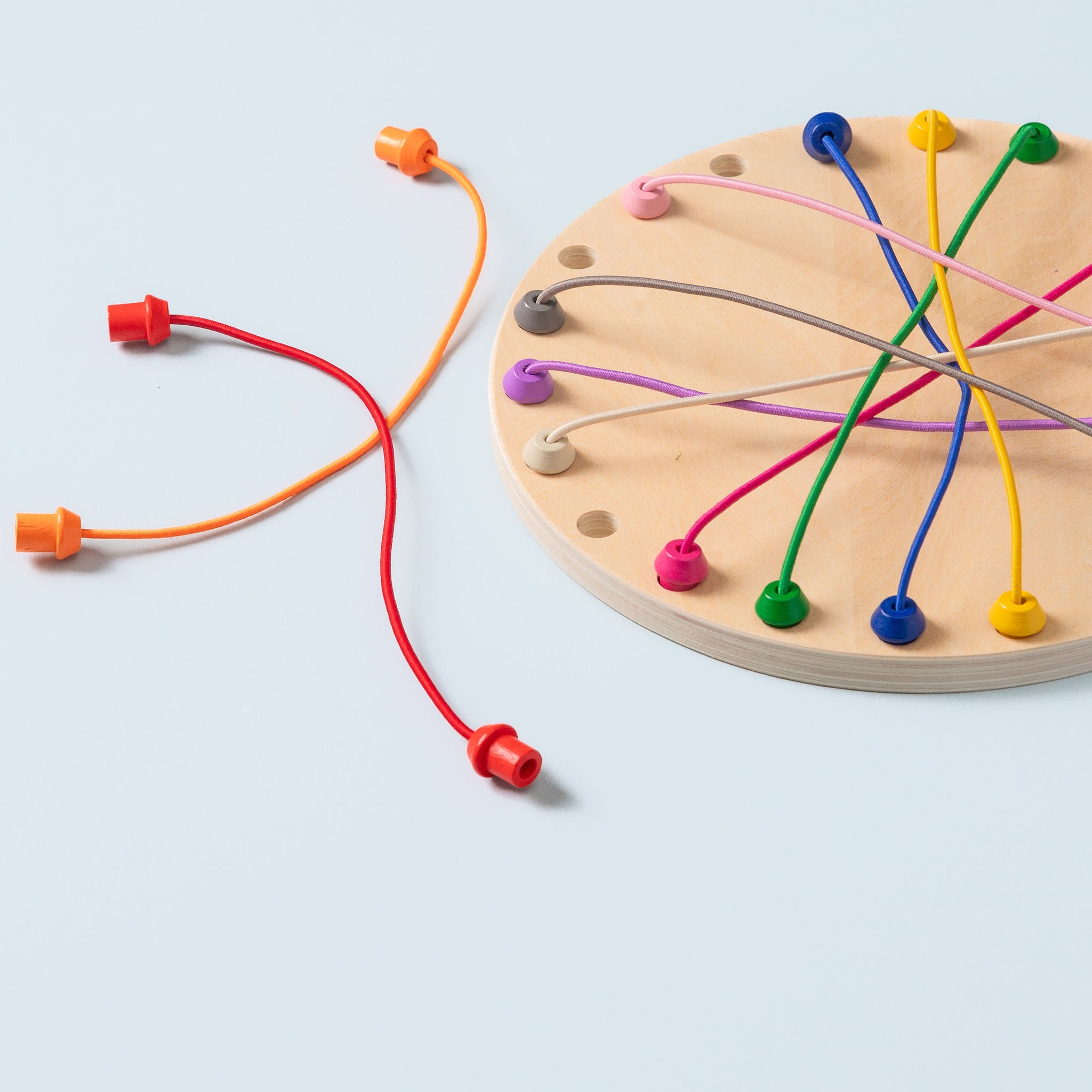 Close-up of rope untangling game board with 22 holes and colourful ropes threaded through