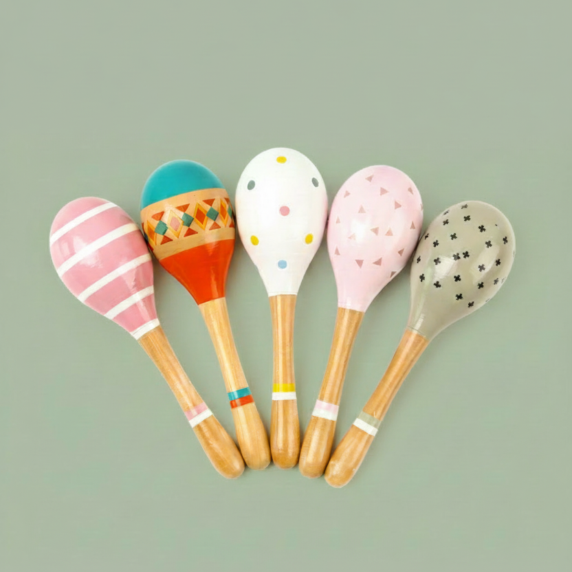 A collection of colorful wooden maracas, each hand-painted with non-toxic, child-safe paints. The maracas come in various colors and patterns, displayed against a white background.