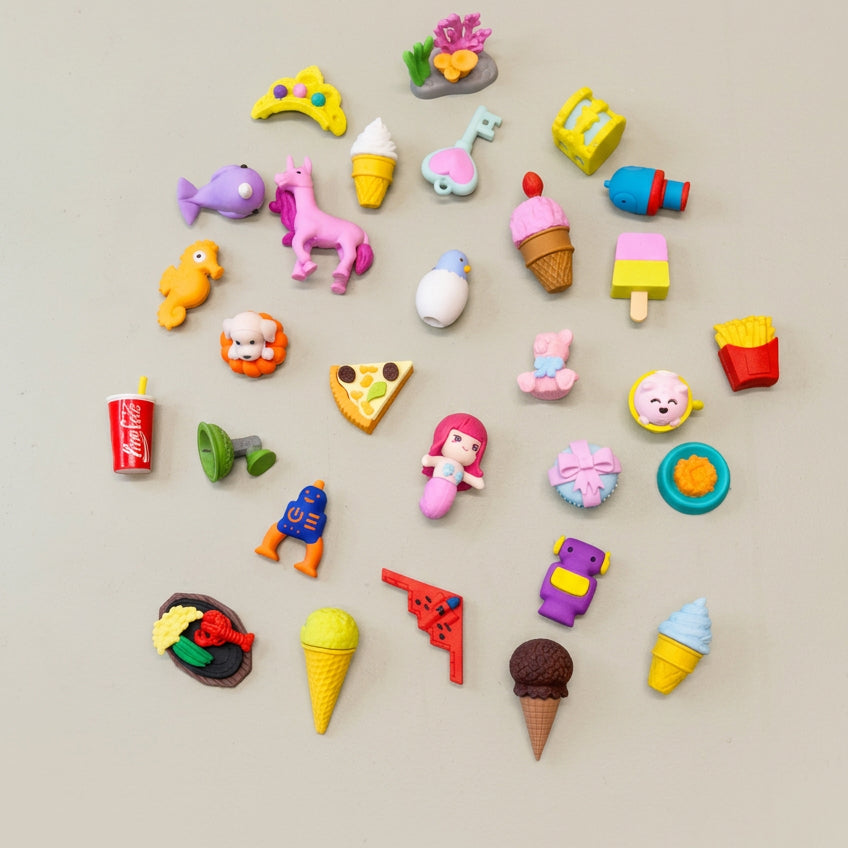 A collection of various mini erasers in different shapes and colors arranged on a grey surface.
