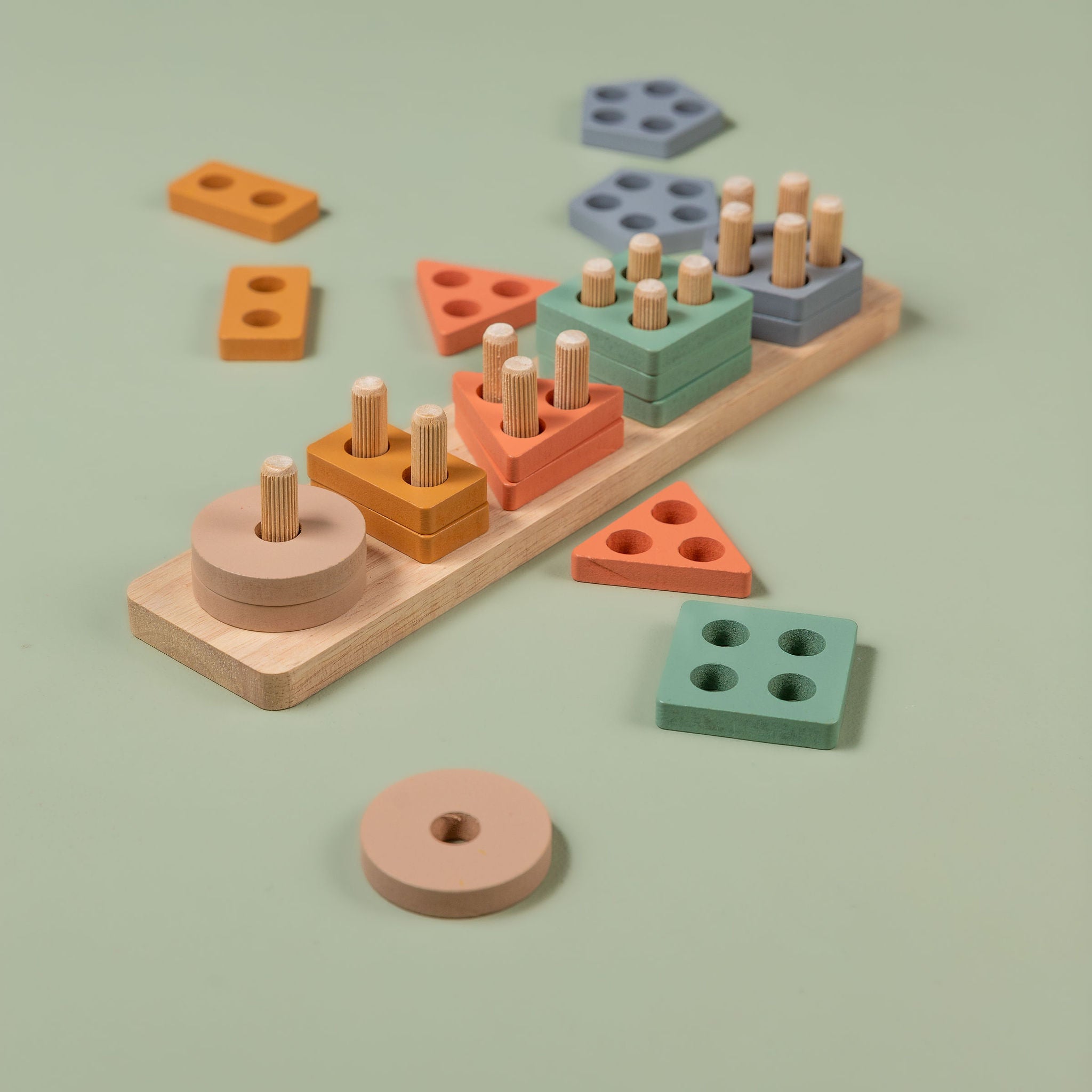 Toddler-friendly wooden shape sorter with pastel coloured geometric blocks arranged on a natural wood baseboard