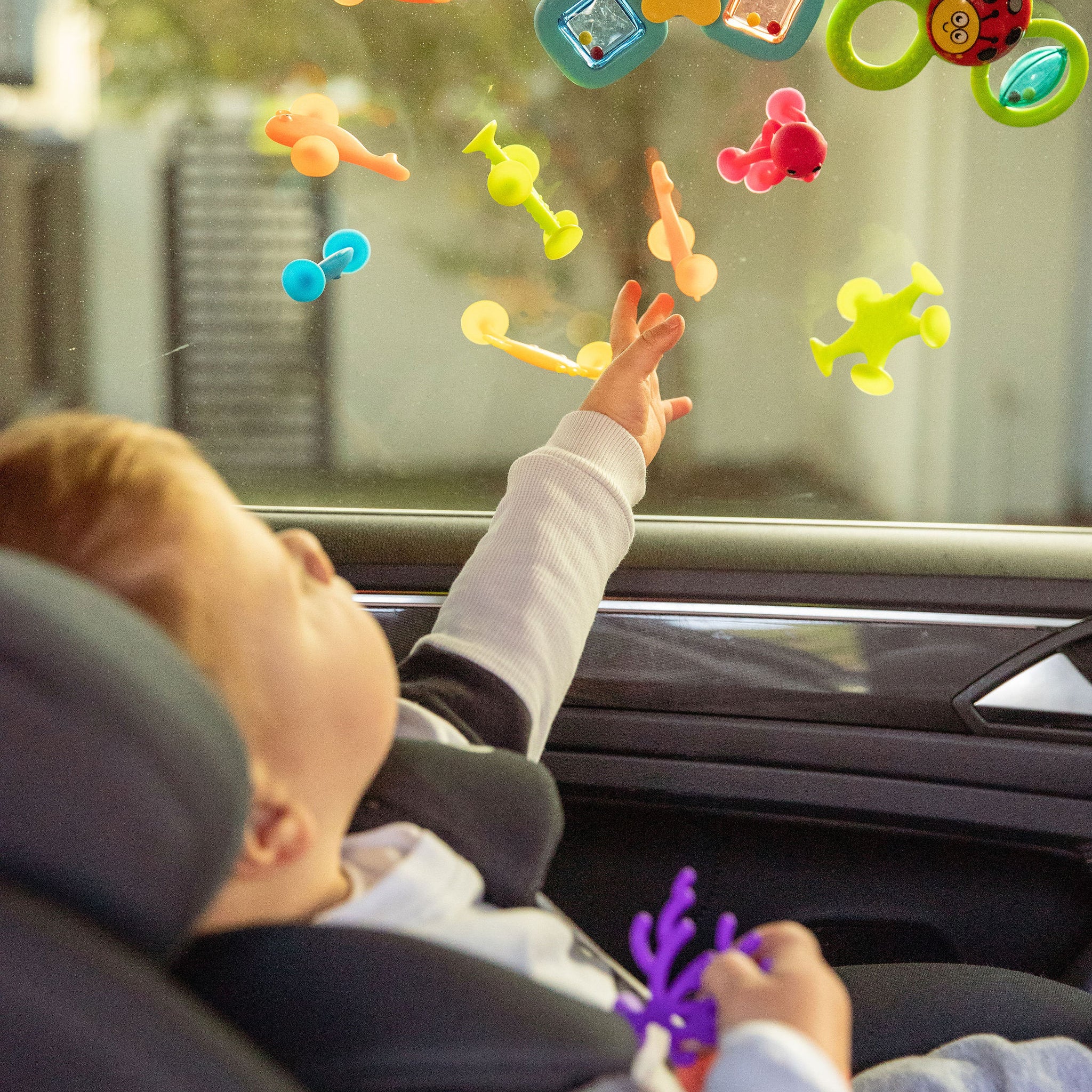 Child playing with colorful window stickers on a car window