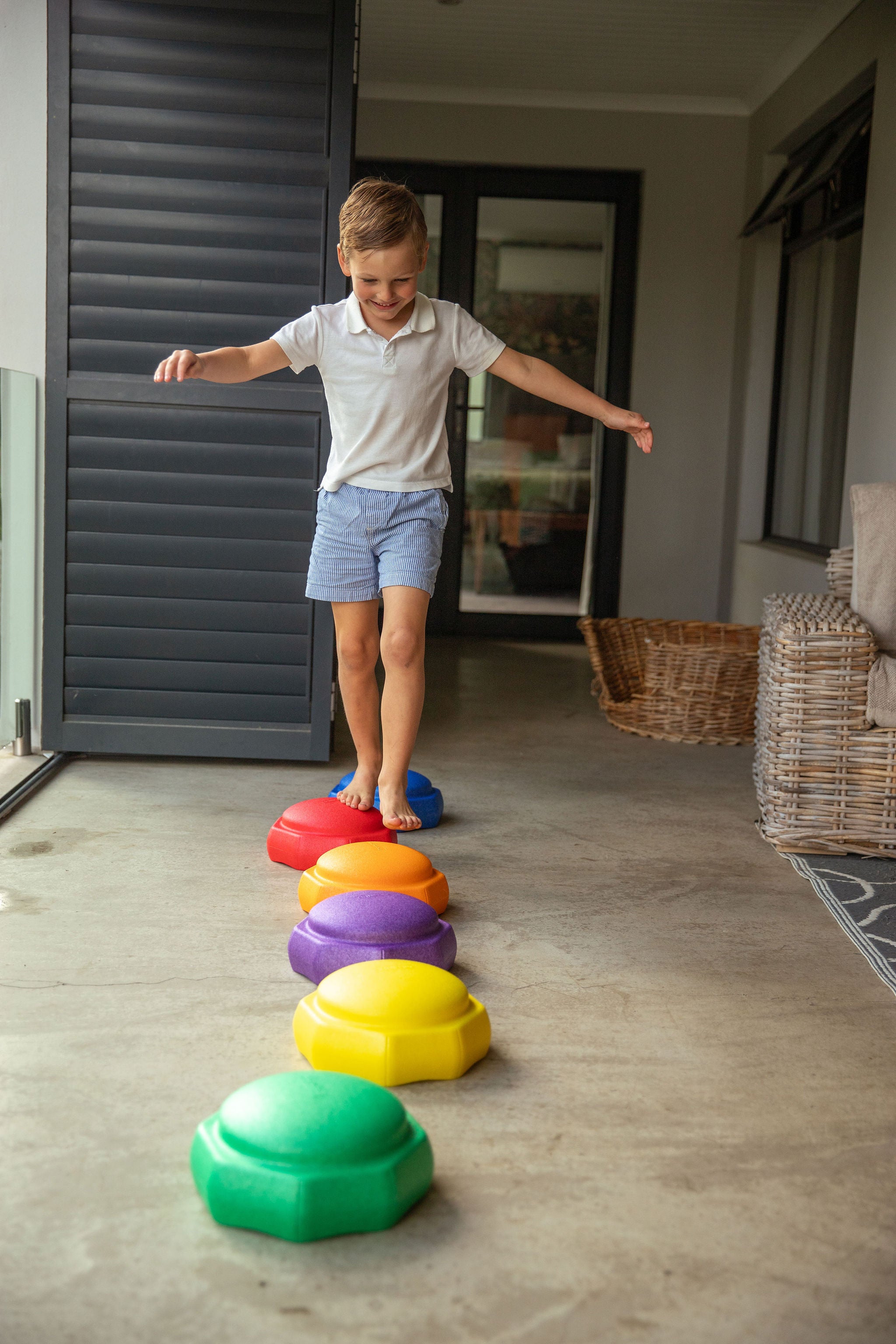 Young child stepping across colourful plastic balance stones, building gross motor and coordination skills