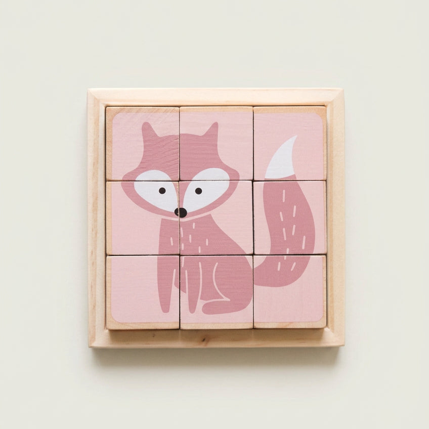 A set of six-sided wooden puzzle blocks with a pink background and a fox illustration on each block, placed on a wooden tray.