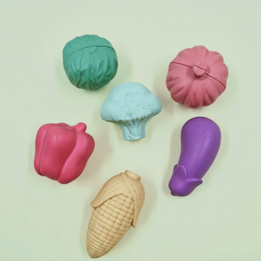 Colorful plastic vegetable-shaped containers on a light background