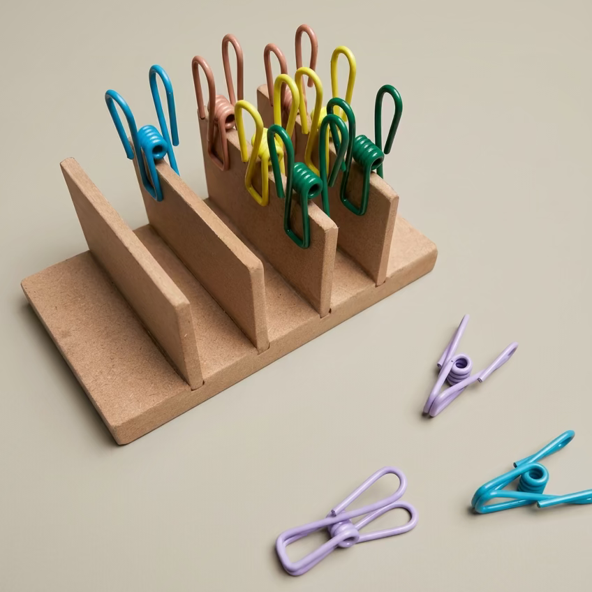 A small wooden stand with wire pegs on nutral back ground