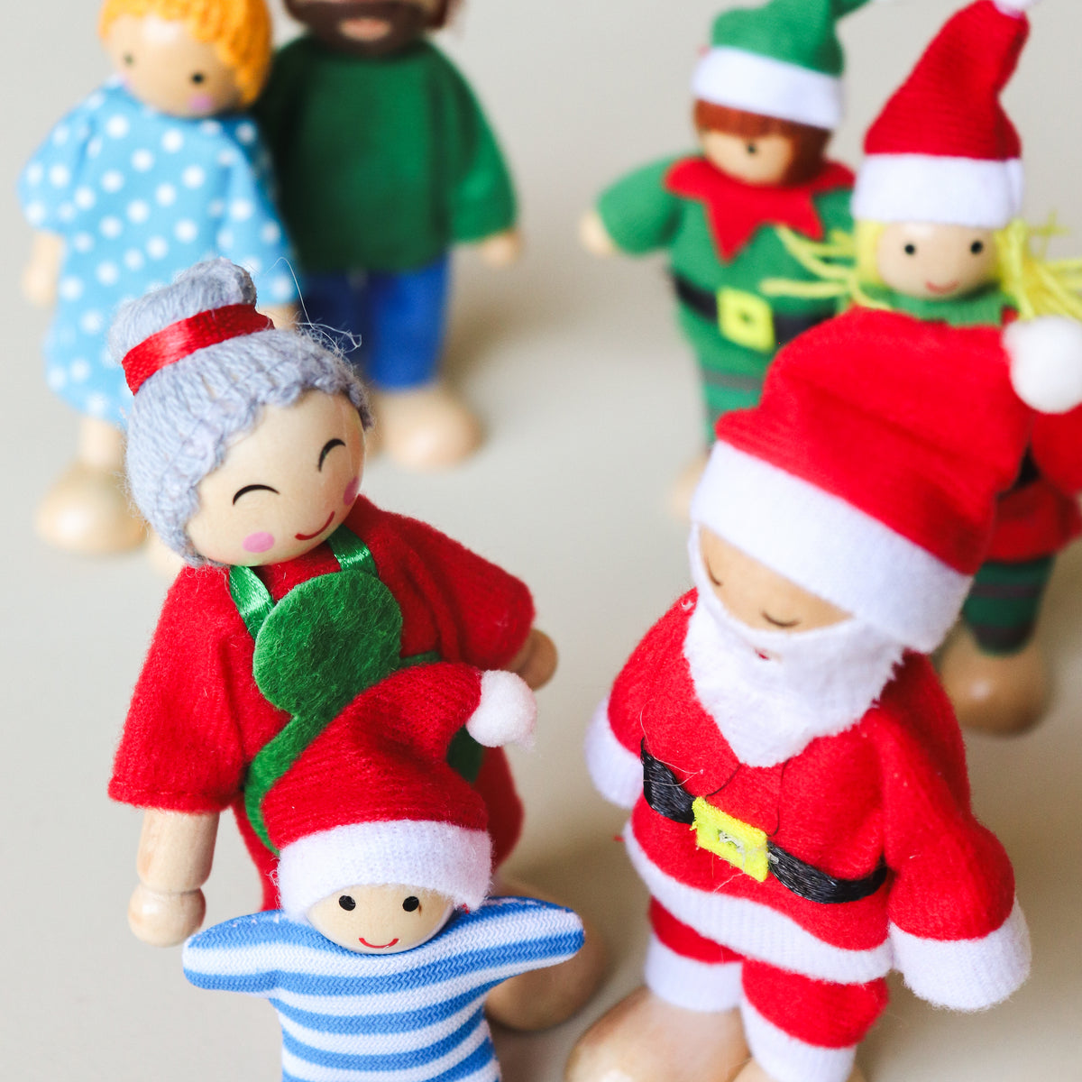 Close-up of the Santa and Mrs Claus bendy dolls showing their painted wooden faces, felt outfits and Santa’s yellow belt buckle.