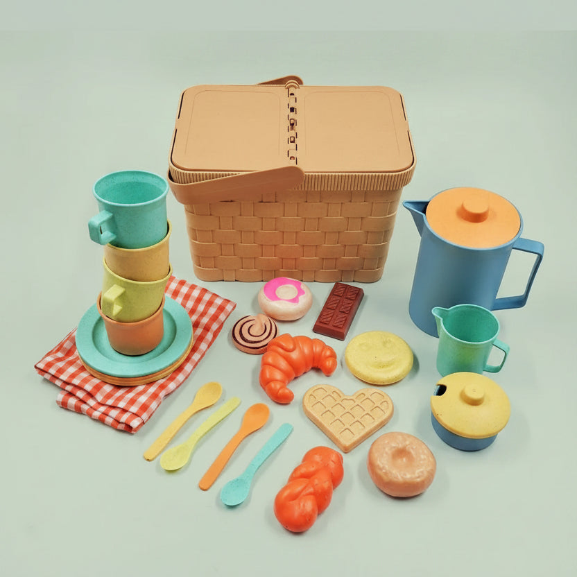 Colorful toy picnic set with a basket, cups, plates, and food items on a light green background.
