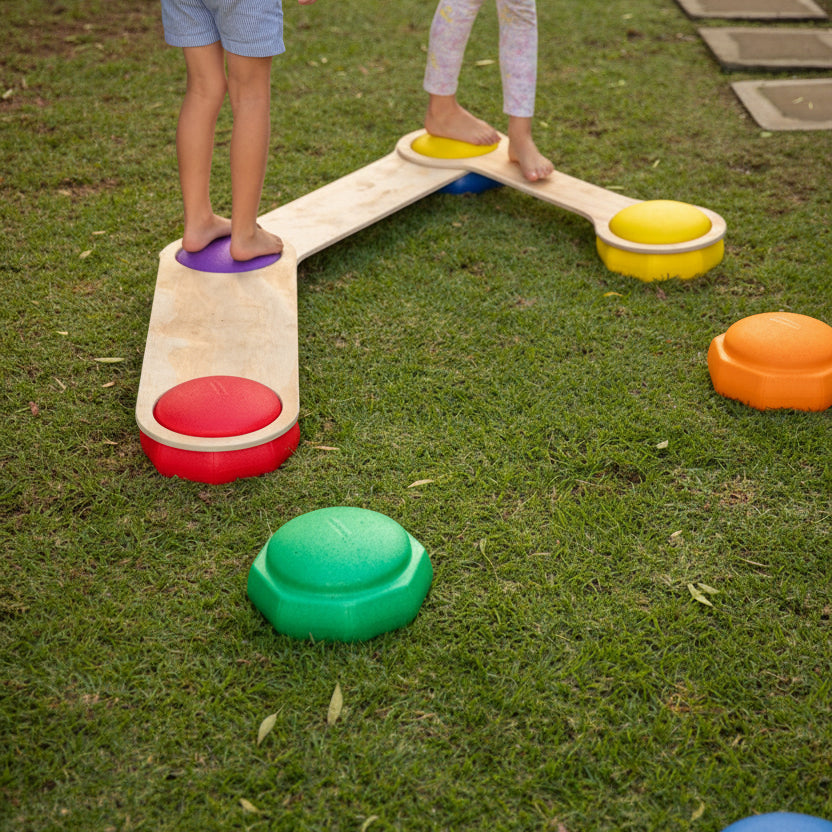 Set of colourful rainbow stepping stones arranged on a wooden floor for children's balance play