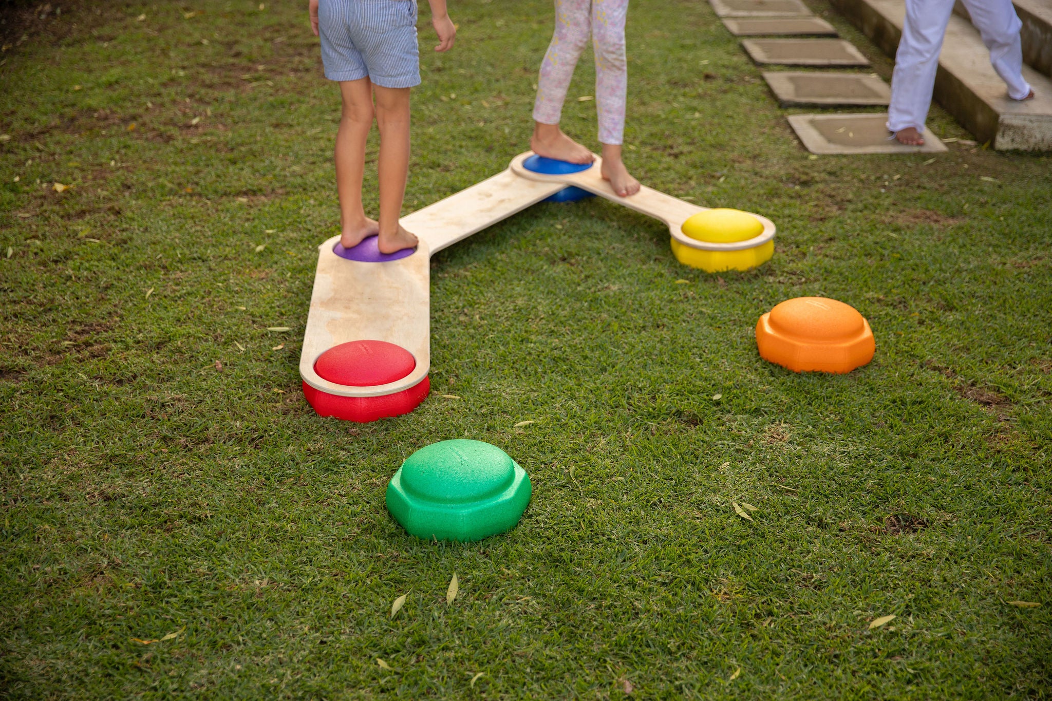Set of colourful rainbow stepping stones arranged on a wooden floor for children's balance play