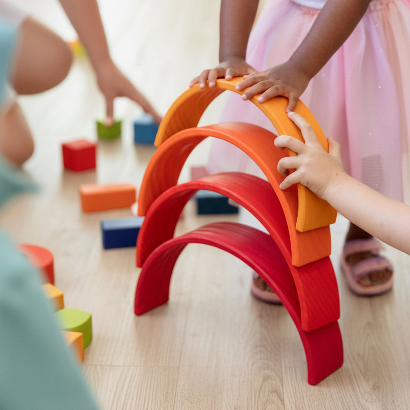 Toddler hands placing a wooden arch onto a rainbow stacker tower — fine motor play