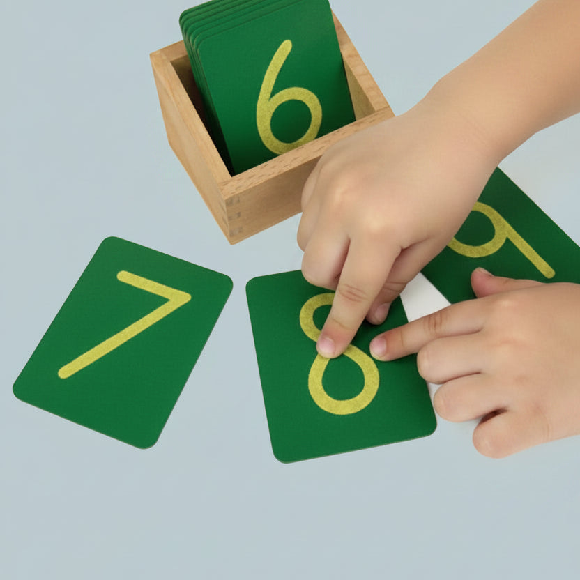 A child tracing a sandpaper numeral with their fingertip, demonstrating the tactile tracing motion.