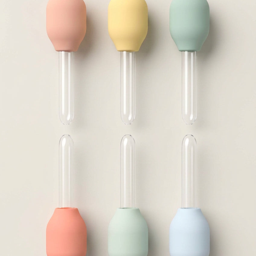Set of six colorful silicone droppers on a white background