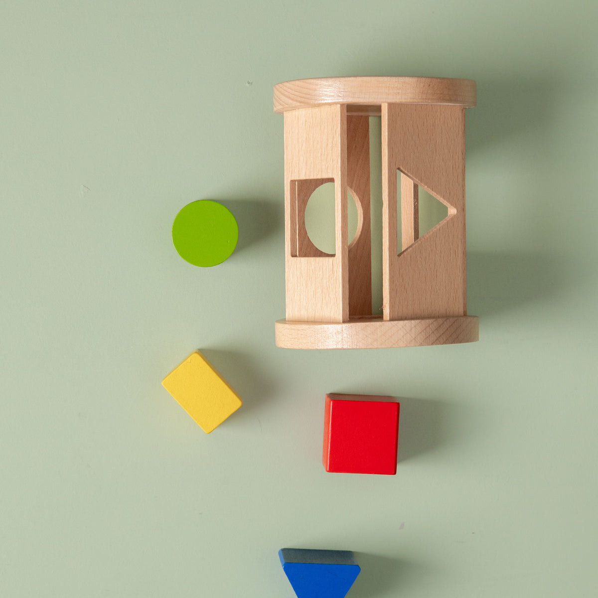 Wooden shape sorter with colorful blocks on a light green background