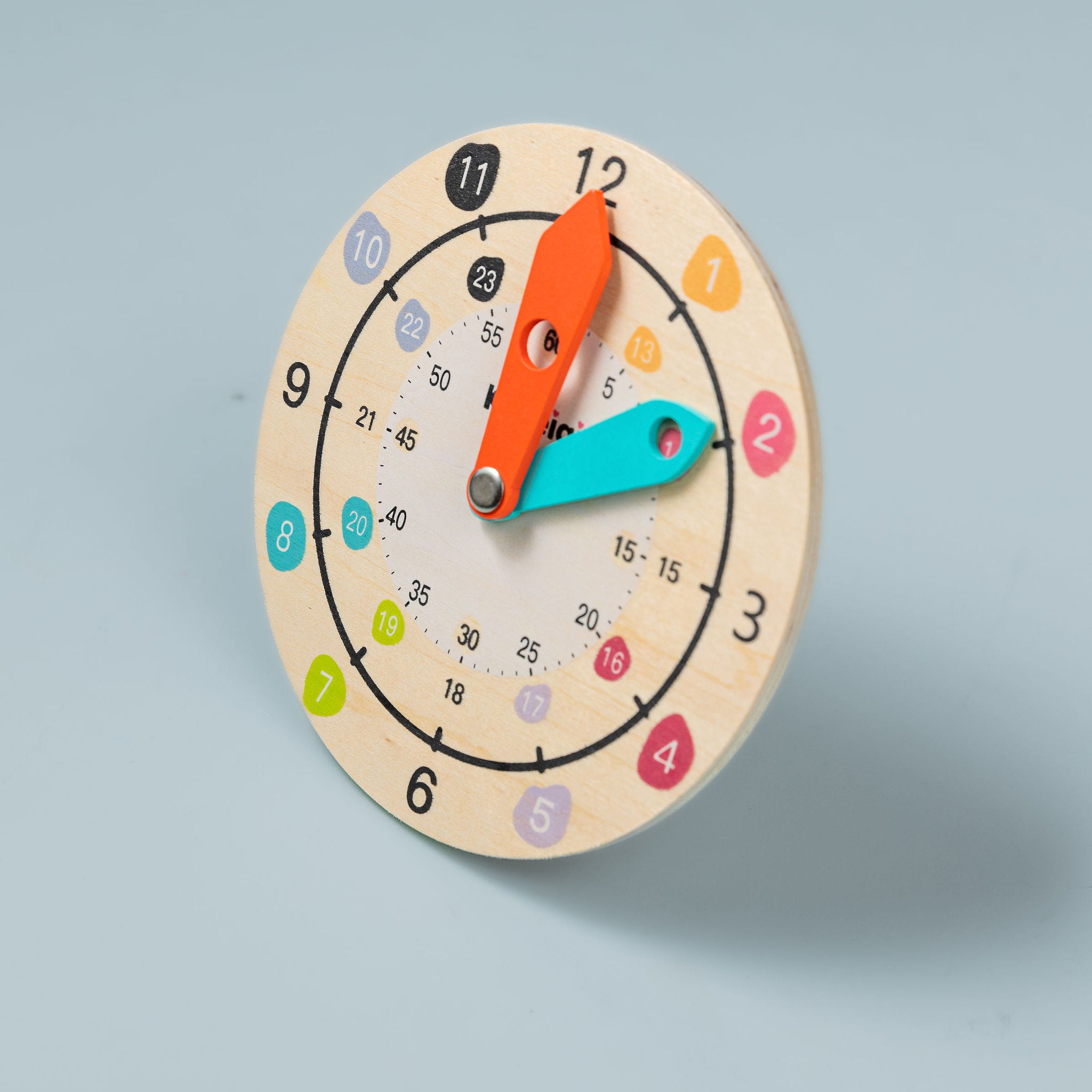 Wooden teaching clock with movable hour and minute hands on white background — analogue time learning toy for kids