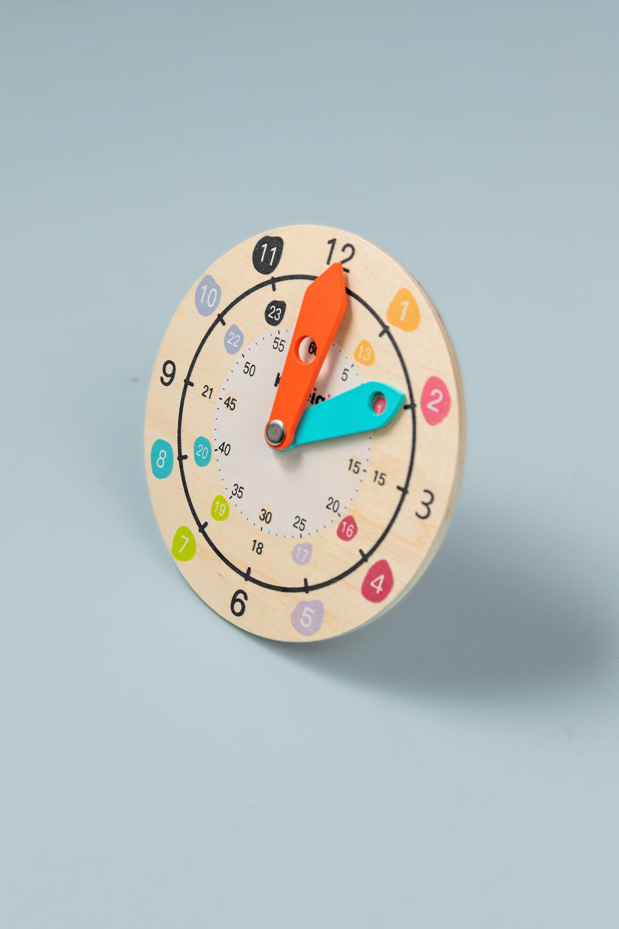 Wooden teaching clock with movable hour and minute hands on white background — analogue time learning toy for kids