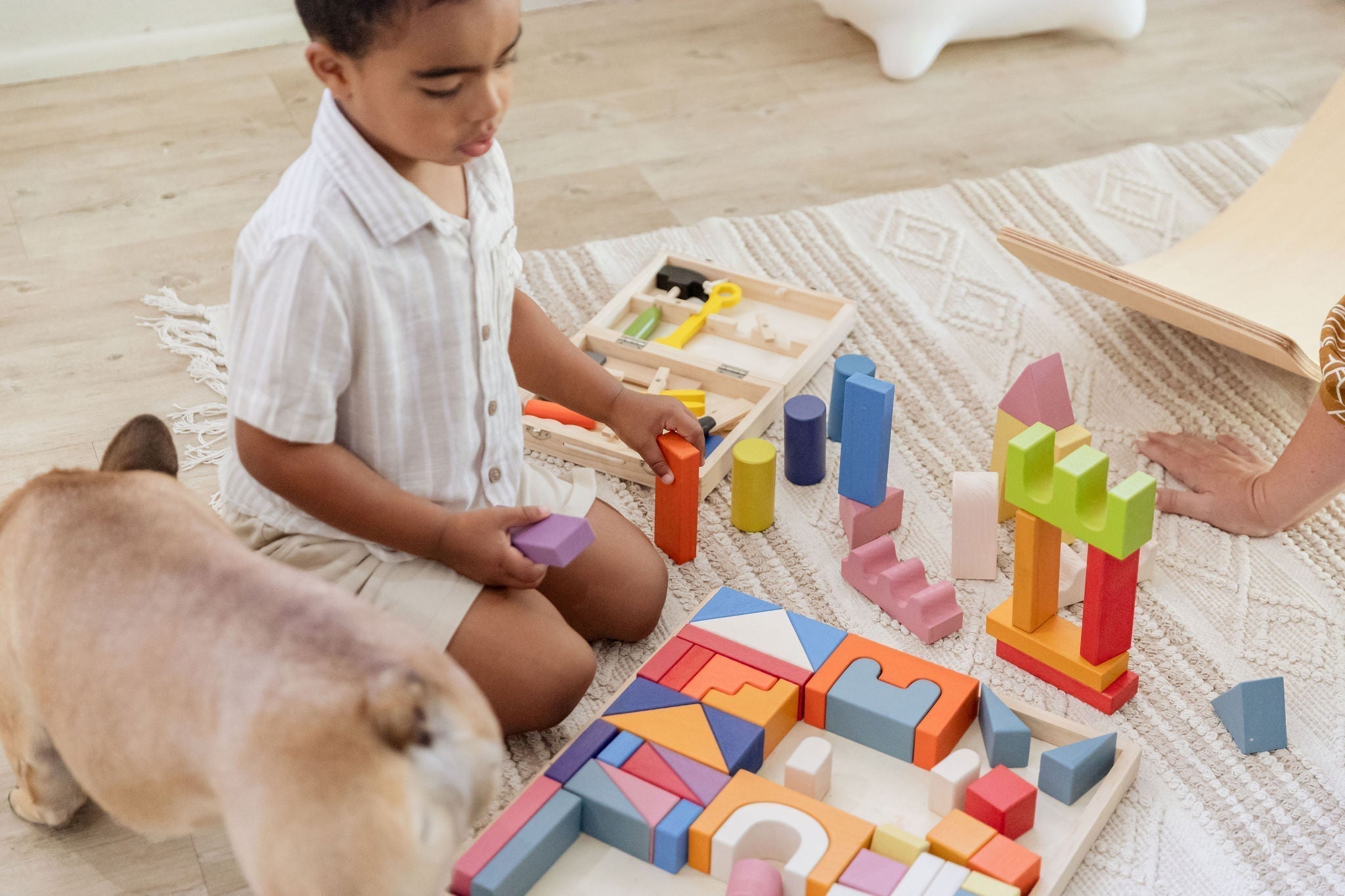 Child playing with wooden open-ended toys on a wooden floor - Tiny Tree Toys South Africa