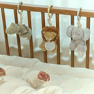 Baby crib with hanging plush toys and a baby's hand reaching out.