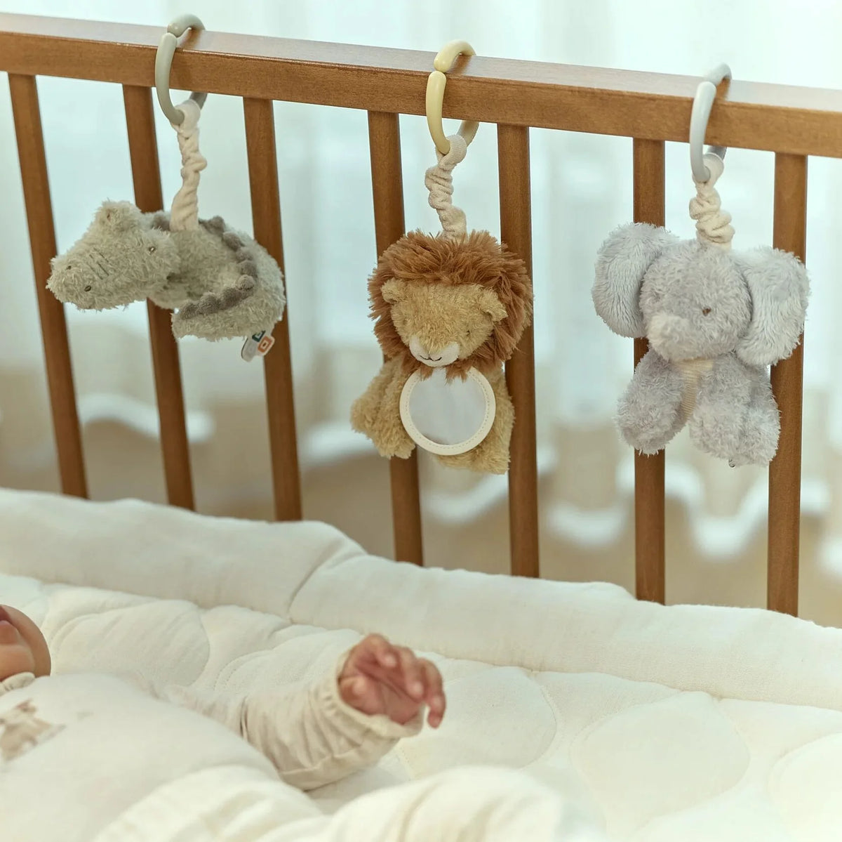 Baby crib with hanging plush toys and a baby's hand reaching out.