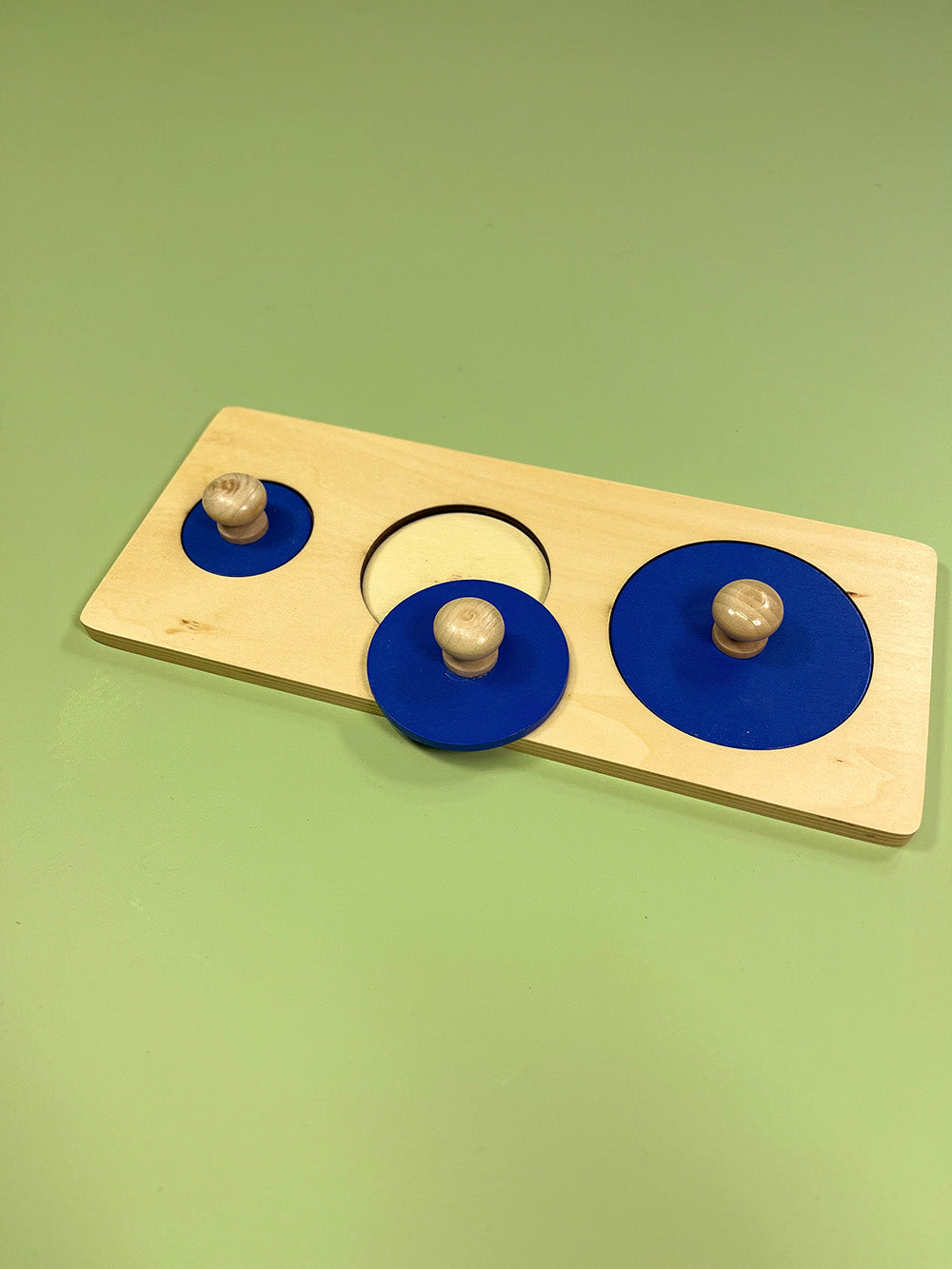 Wooden puzzle with blue circular pegs and wooden knobs on a green background
