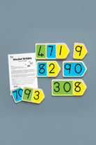 Number Builder educational toy set with colorful arrow-shaped tiles displaying numbers 1 through 9 and a printed instruction sheet on a white background.