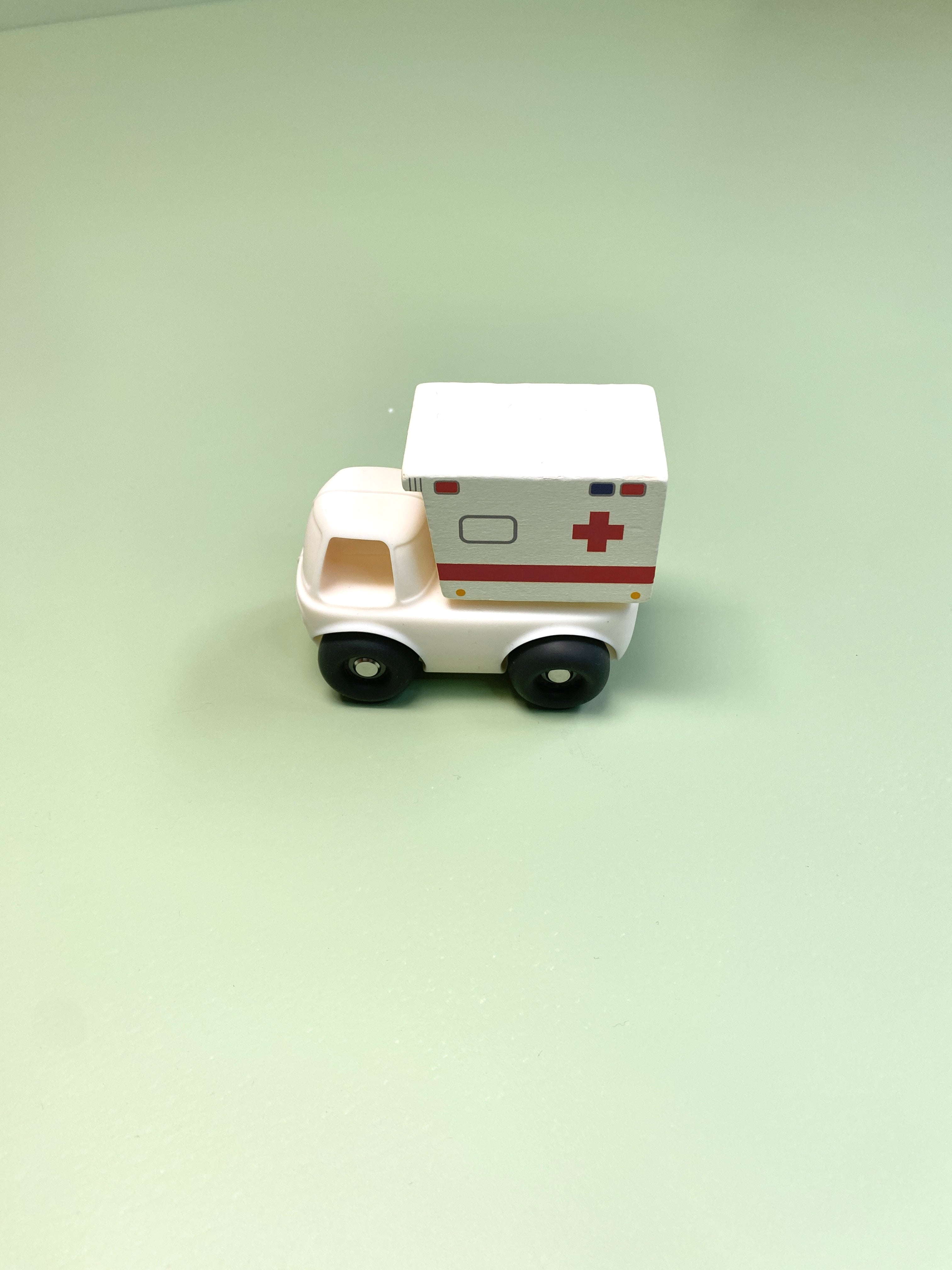 Toy silicone and wooden ambulance on a light green background