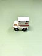 Toy silicone and wooden ambulance on a light green background