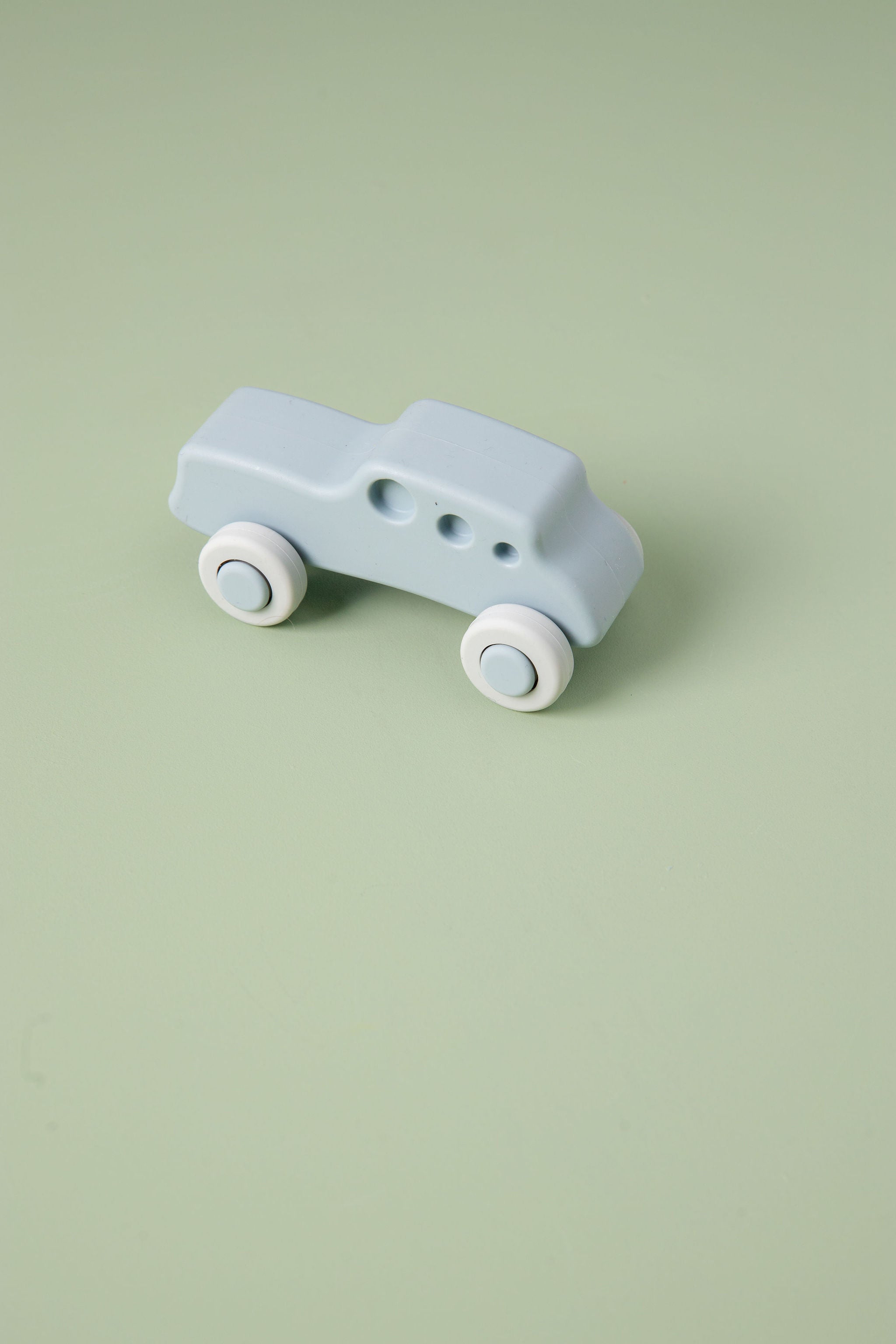 Light blue toy car with white wheels on a light green background