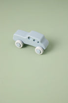 Light blue toy car with white wheels on a light green background