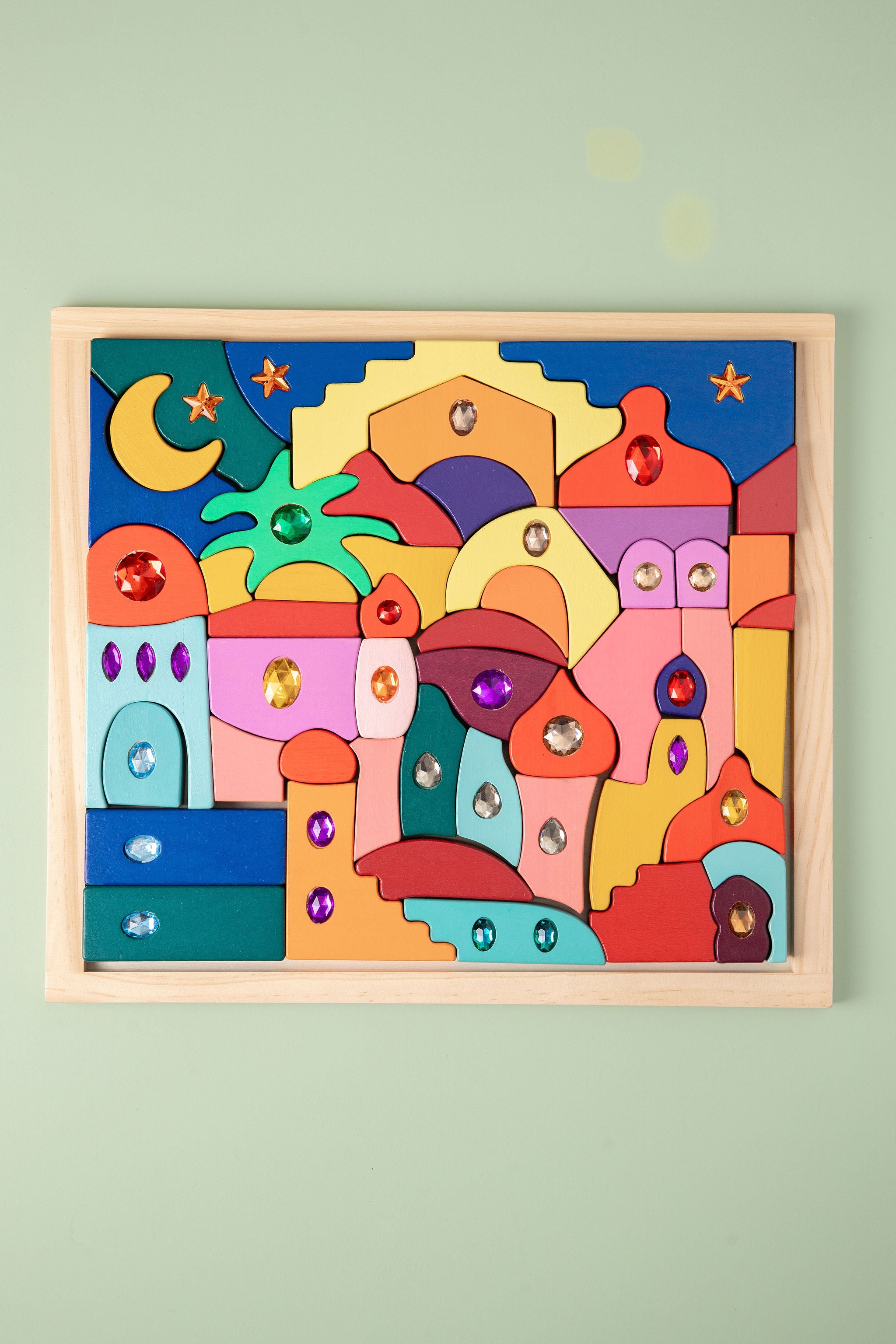 Colorful children's puzzle with wooden frame on a light green wall