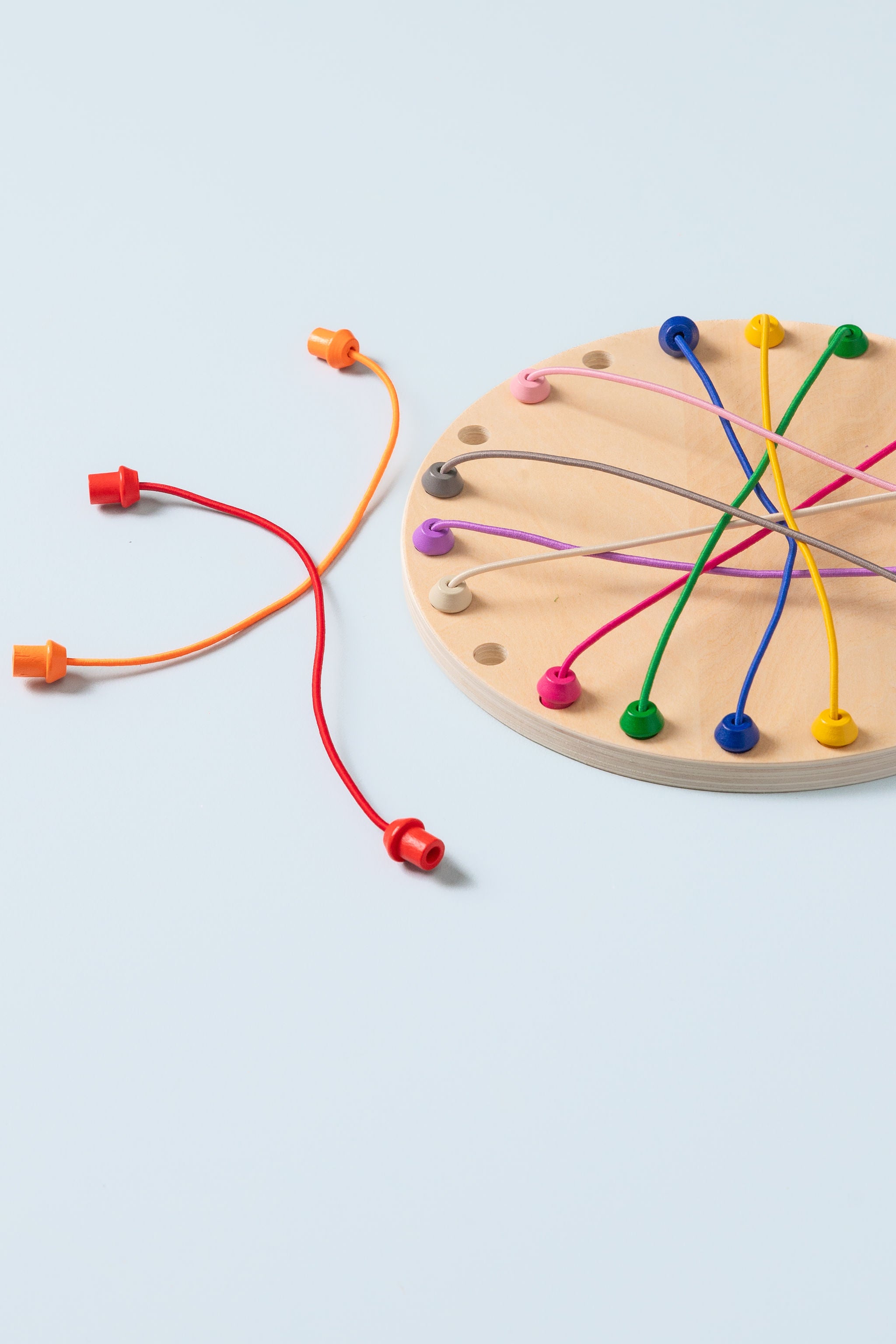 Close-up of rope untangling game board with 22 holes and colourful ropes threaded through