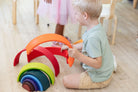 Child playing with rainbow stacker arches on a play mat — open-ended Montessori building 
