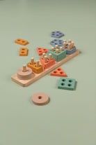 Toddler-friendly wooden shape sorter with pastel coloured geometric blocks arranged on a natural wood baseboard