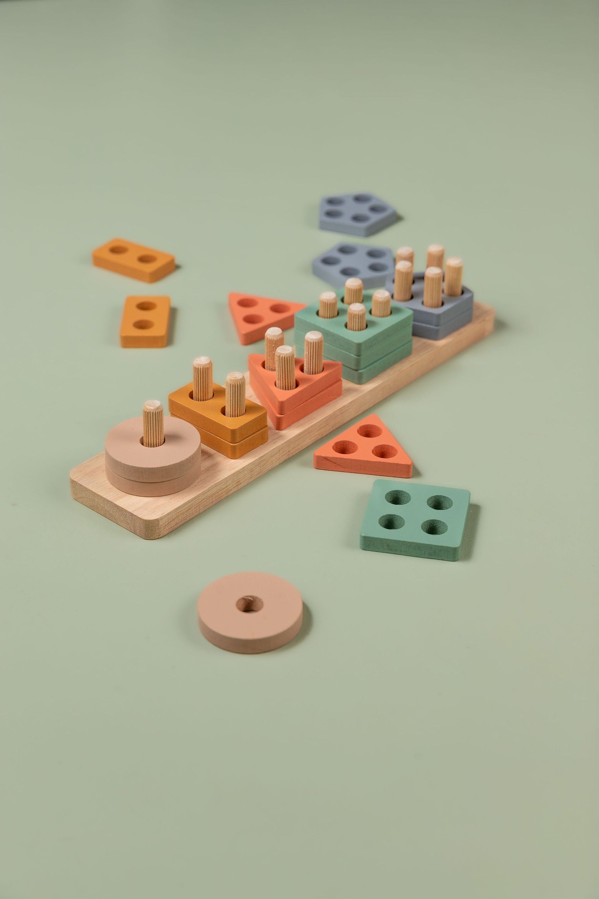 Toddler-friendly wooden shape sorter with pastel coloured geometric blocks arranged on a natural wood baseboard