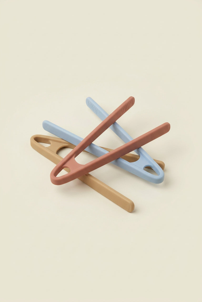 Three silicone  tongs in different colors on a light gray background