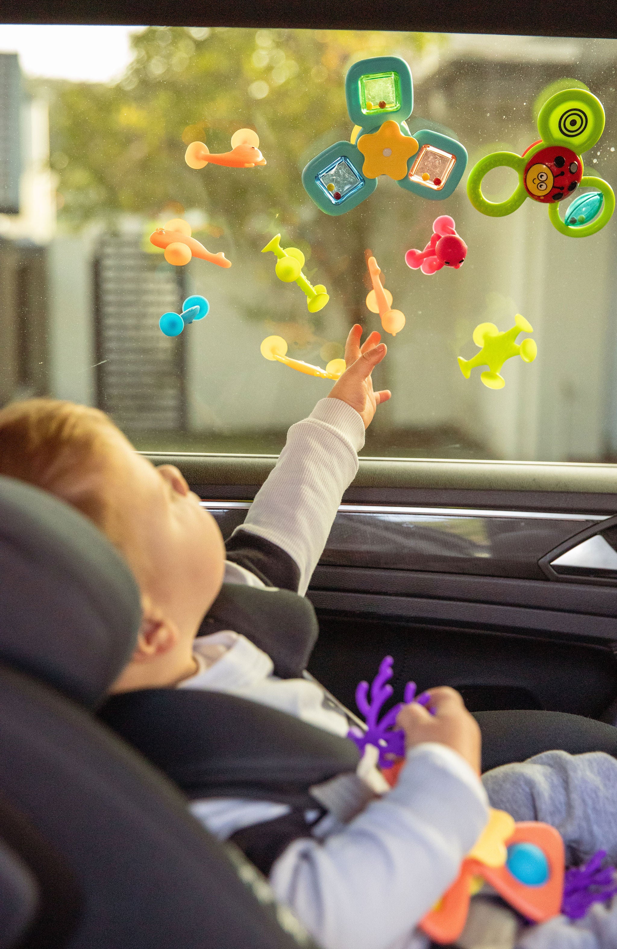 Child playing with colorful window stickers on a car window