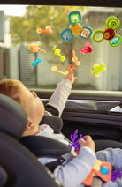 Child playing with colorful window stickers on a car window