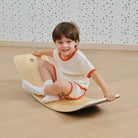 Child balancing on wooden wobble board indoor play