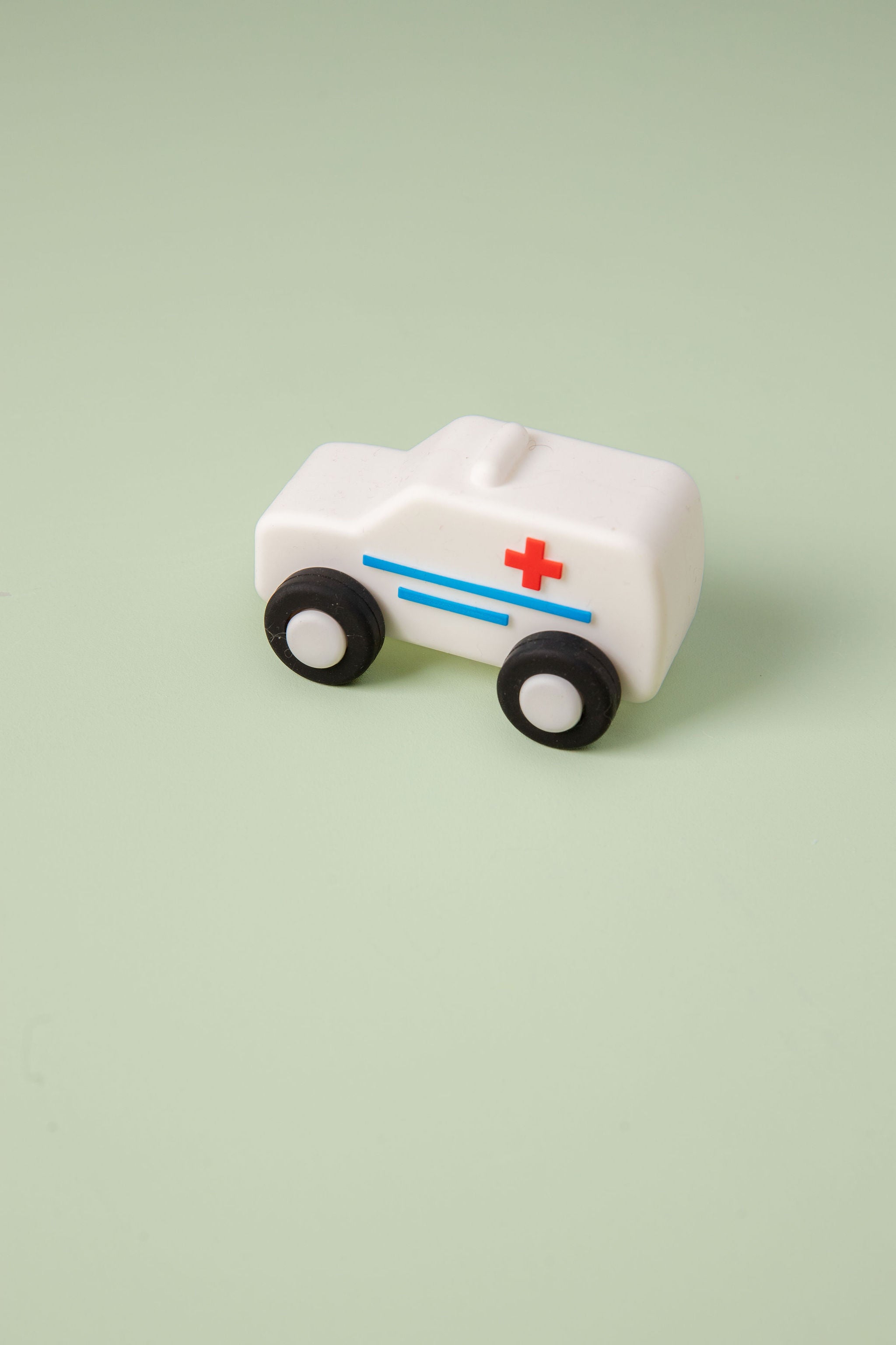 White toy ambulance with a red cross on a light green background