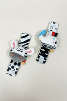 Two plush baby rattle toys shaped like zebra heads, displayed on a liOne rattle features black and white stripes with pink inner ears and a gray snout. wrist rattle high contrast 