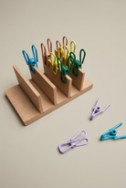 A small wooden stand with wire pegs on nutral back ground