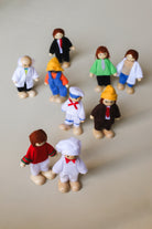 A set of nine wooden dolls representing various occupations, including a scientist, doctor, engineer, sailor, business man, chef, farmer, athlete, and teacher, each dressed in attire appropriate to their profession.