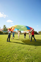 Children playing with a large, colorful parachute outdoors.