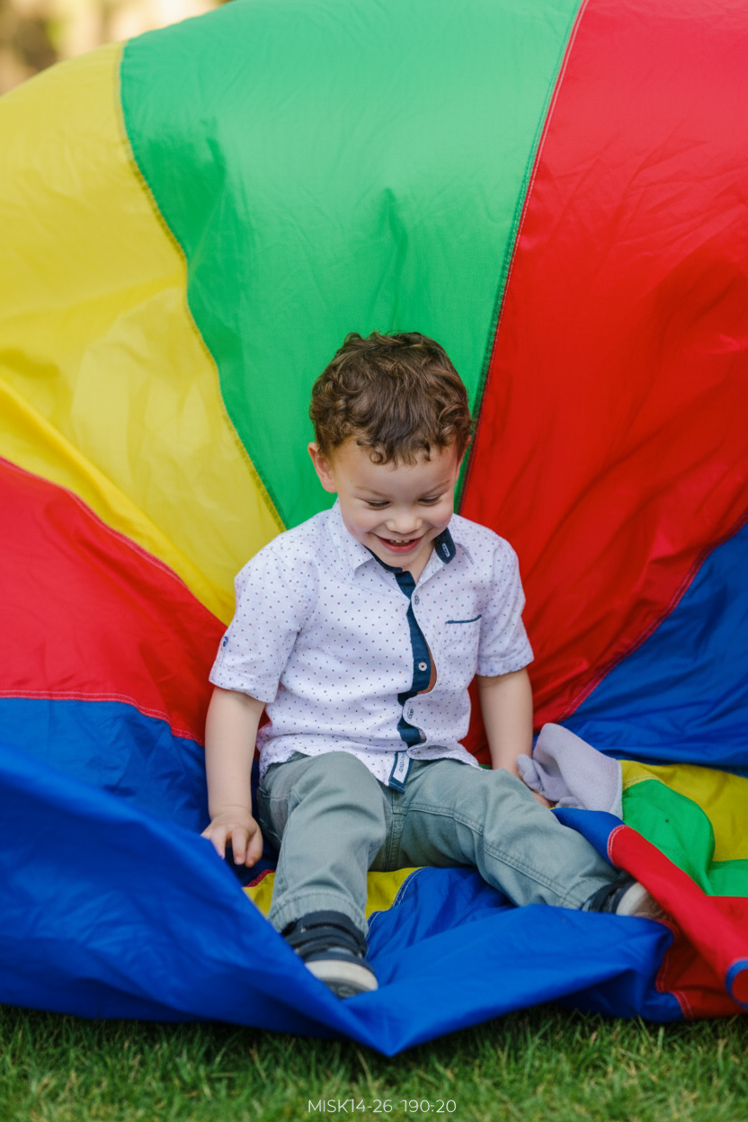 boy sitting on big colourful parachute- gross motor play