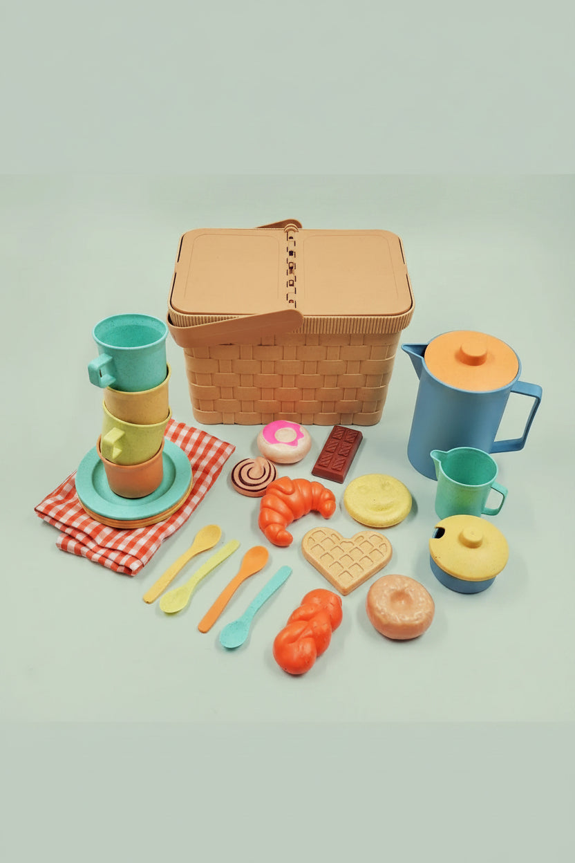 Colorful toy picnic set with a basket, cups, plates, and food items on a light green background.