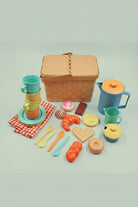 Colorful toy picnic set with a basket, cups, plates, and food items on a light green background.