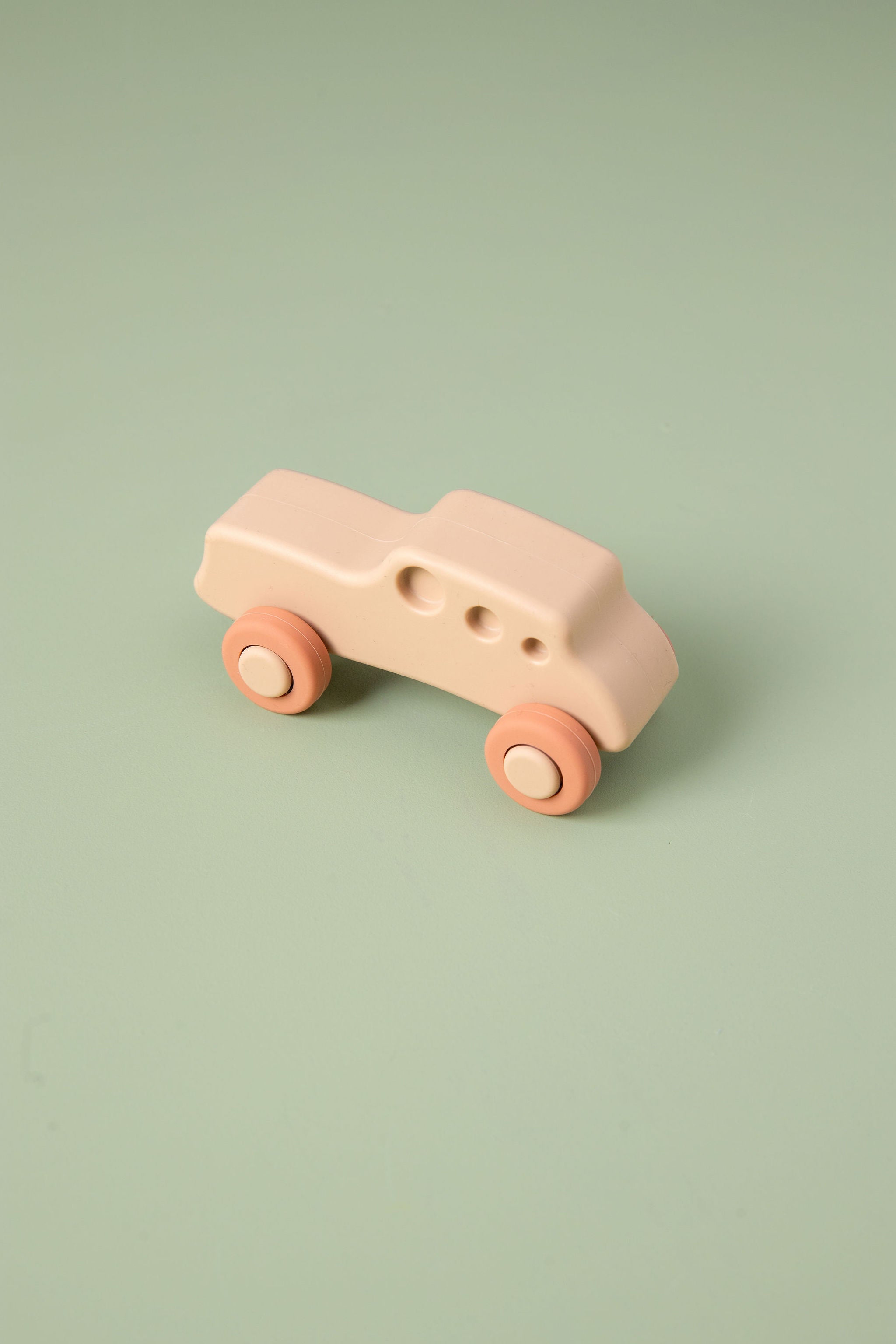 Small pink silicone  car on a light green background