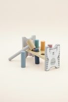 A wooden toy block hammer set by PolarB, featuring a light natural wood mallet, colorful wooden pegs in blue, teal, orange, pink, and navy, and a white bear-themed guard with gray stripes.